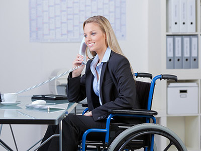 Eine Frau in einem Rollstuhl spricht am Telefon in einem Büro.