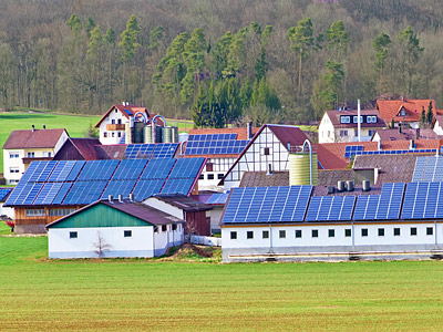 Eine ländliche Landschaft mit mehreren Gebäuden und Solarpaneelen auf den Dächern.